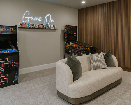 Down to Earth Projects | Utah Valley Parade at The Legacy at Meadow Ridge - game room with pinball machine pac man video game and a sofa 
